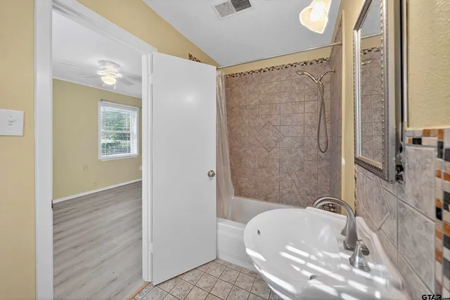 an empty room with wooden floor ceiling fan and windows