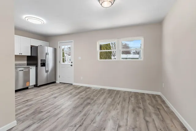 a view of a kitchen with a refrigerator a stove top oven cabinets and wooden floor