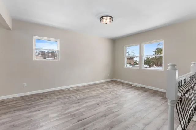 a view of an empty room with window and wooden floor
