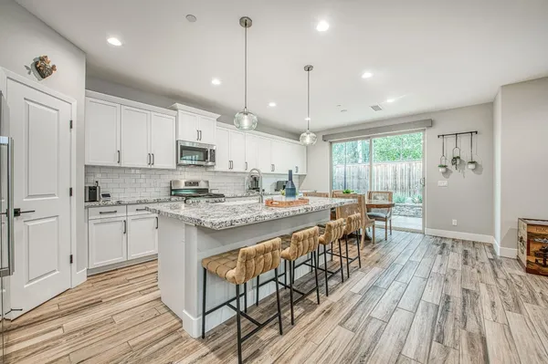 a large kitchen with granite countertop lots of counter space a sink appliances and cabinets