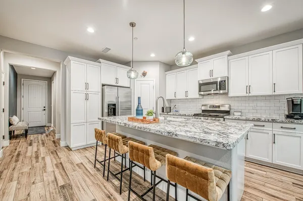 a kitchen with granite countertop kitchen island stainless steel appliances a dining table and chairs