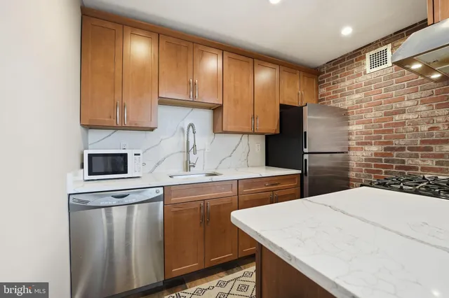 a kitchen with stainless steel appliances a sink a stove a refrigerator a microwave and cabinets