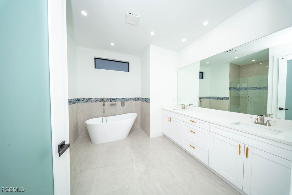 2819 34th Street West Lehigh Acres, FL 33971 - Photo 7 of 41 a bathroom with a double vanity sink mirror and bathtub