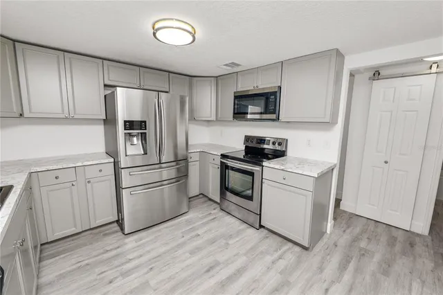 a kitchen with white cabinets and stainless steel appliances