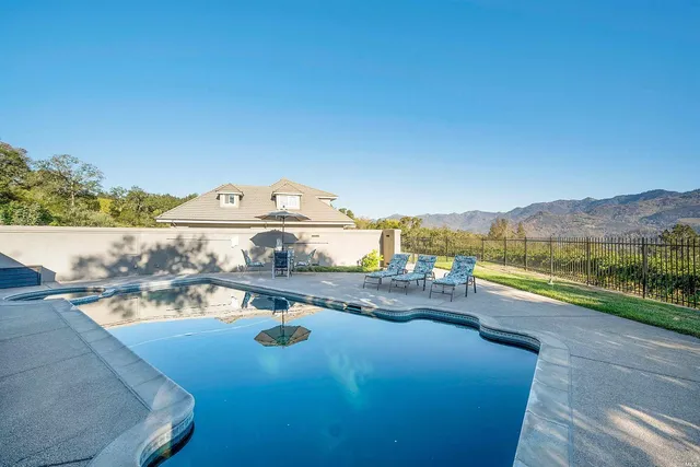 a view of swimming pool with a table and chairs under an umbrella
