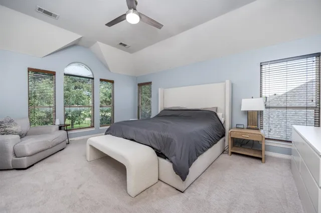 a spacious bedroom with a bed couch and windows