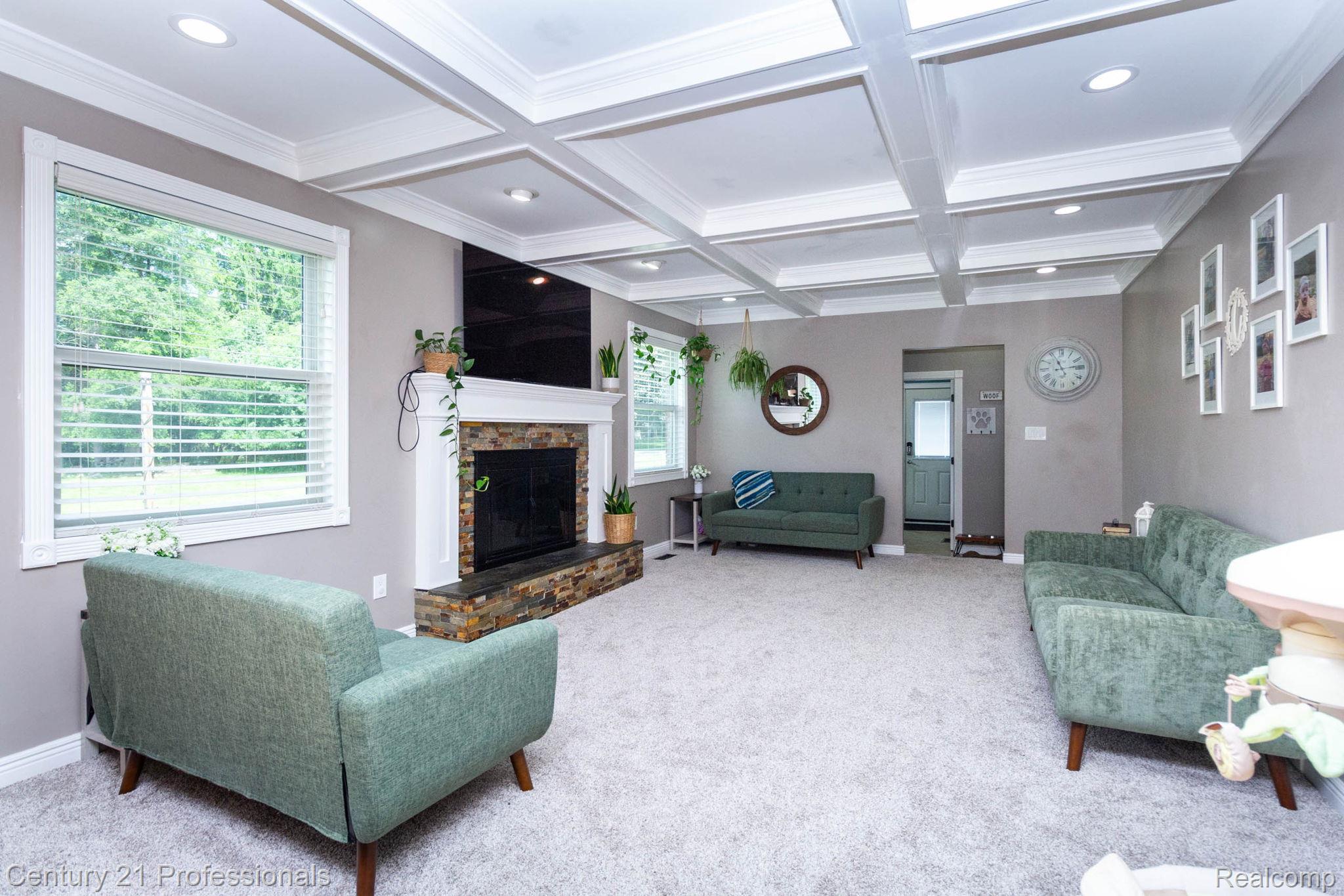 671 Bridgestone Drive Rochester, MI 48309 - Photo 16 of 50 Spacious living area featuring a coffered ceiling with recessed lighting, a stone-clad fireplace with a white mantel, and light-colored carpeting