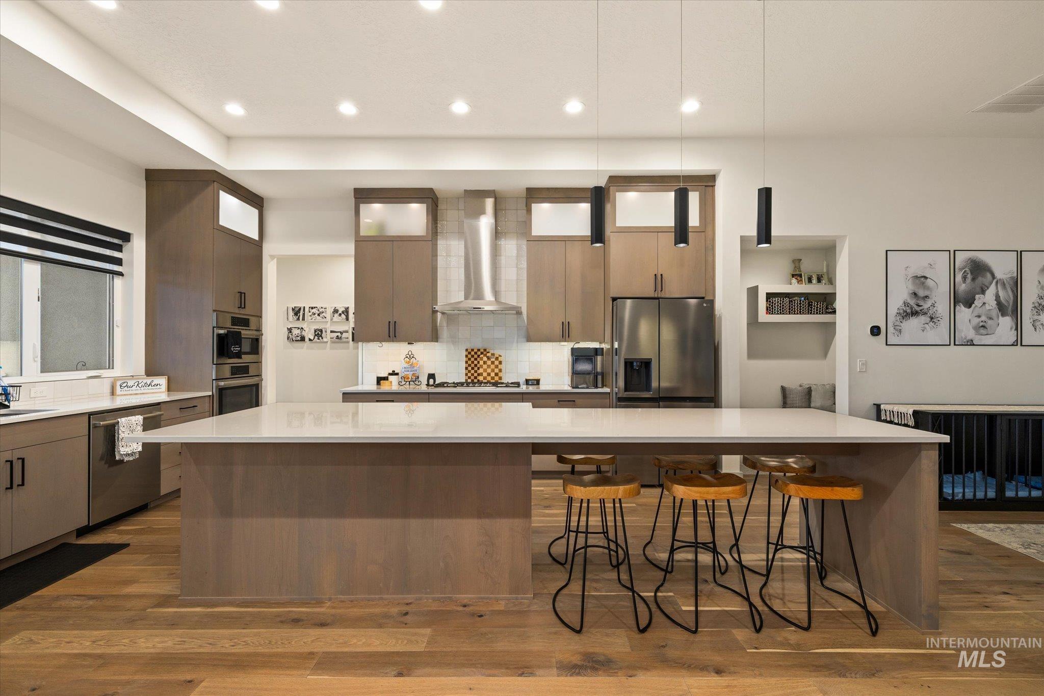 2250 South Steichen Way Meridian, ID 83642 - Photo 11 of 40 Kitchen featuring decorative light fixtures, a large island, appliances with stainless steel finishes, a breakfast bar area, and wall chimney exhaust hood