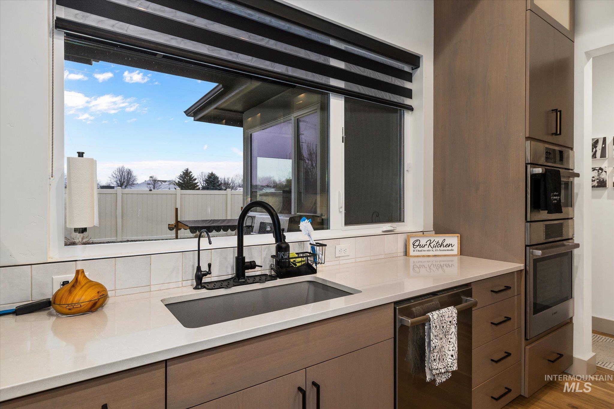 2250 South Steichen Way Meridian, ID 83642 - Photo 13 of 40 Kitchen with stainless steel appliances, light stone counters, light wood-style flooring, and decorative backsplash