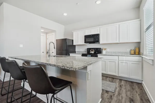 a kitchen with granite countertop white cabinets and stainless steel appliances