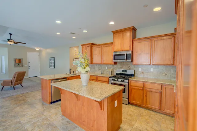 a kitchen with stainless steel appliances granite countertop a stove top oven a sink dishwasher and a refrigerator with wooden floor