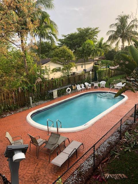 8978 West Sample Road, Unit 203 Coral Springs, FL 33065 - Photo 13 of 13 a view of a swimming pool with lawn chairs under an umbrella