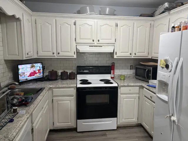 a kitchen with granite countertop white cabinets and white appliances