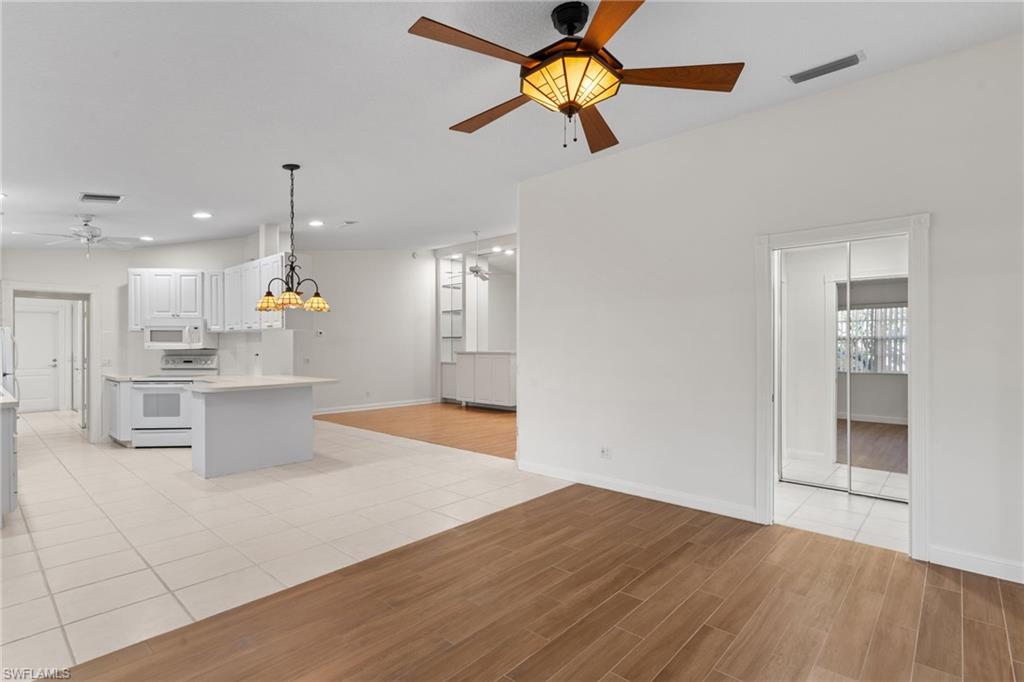 4907 Kingston Way Naples, FL 34119 - Photo 15 of 49 a kitchen with stainless steel appliances kitchen island granite countertop a refrigerator a stove and a wooden floors