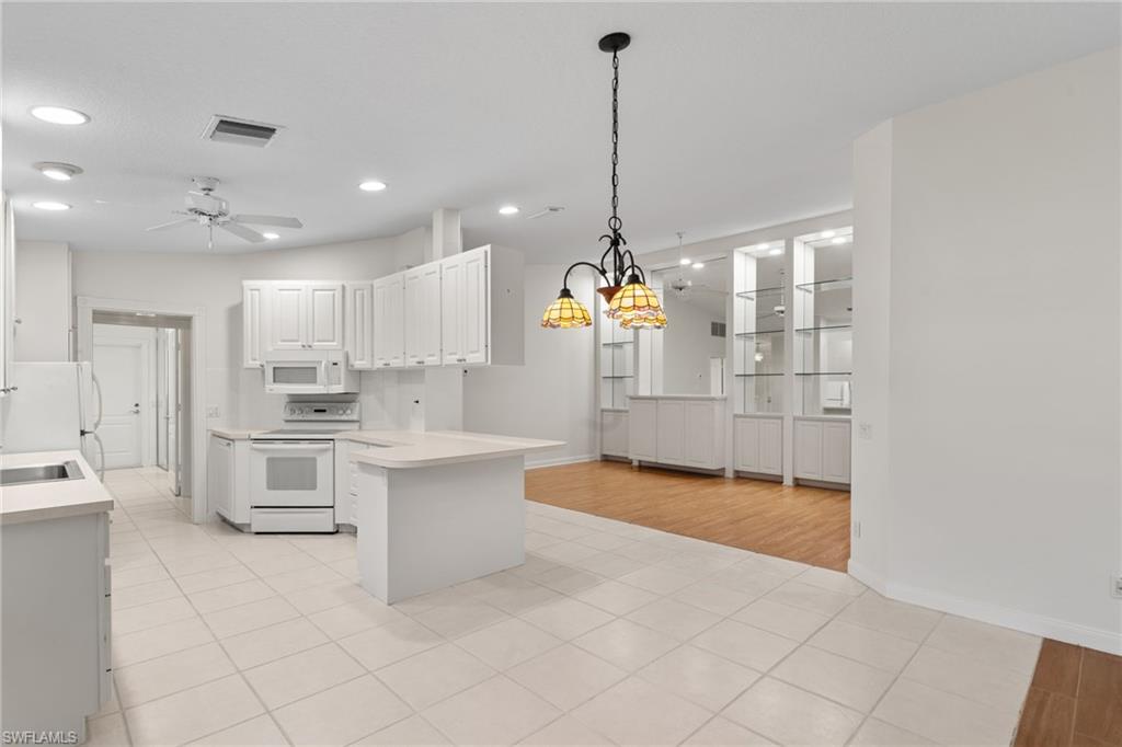 4907 Kingston Way Naples, FL 34119 - Photo 36 of 49 a large white kitchen with kitchen island white cabinets and stainless steel appliances