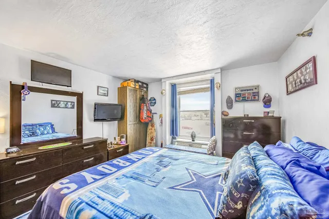 a bedroom with a bed and a flat tv screen on the dresser