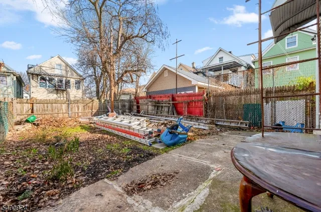 a view of a white house with a small yard and large trees