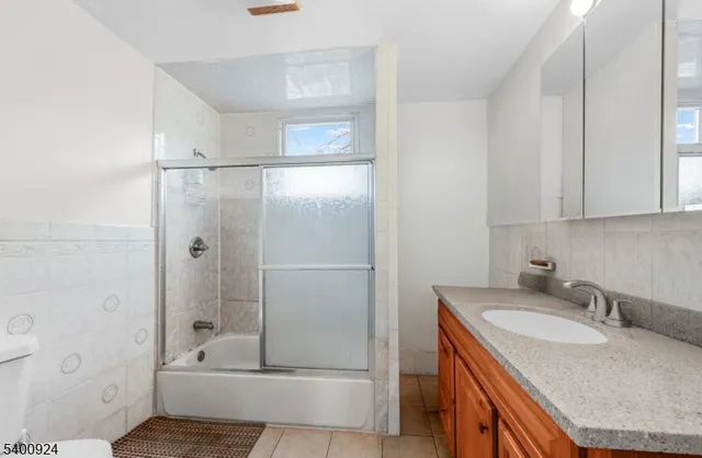 a bathroom with a granite countertop sink and mirror with bathtub