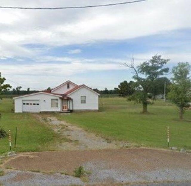 White single-story residence with an attached garage, red roof, and a gravel driveway