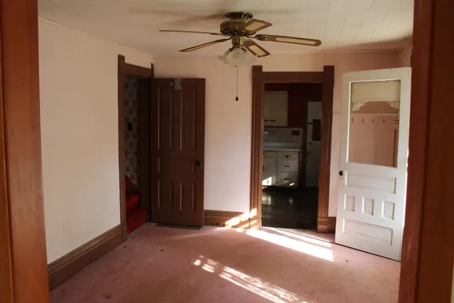 an empty room with closet and a chandelier fan