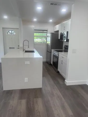 a kitchen with kitchen island white cabinets and stainless steel appliances