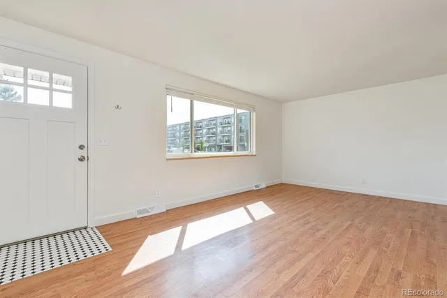 an empty room with wooden floor and windows