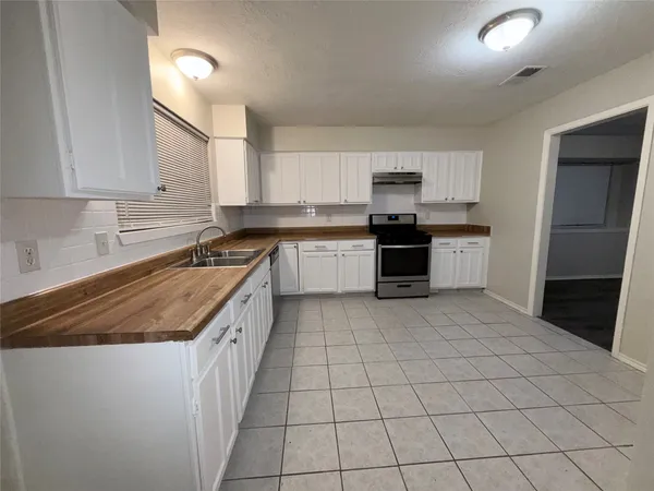 a kitchen with a sink a stove top oven and white cabinets