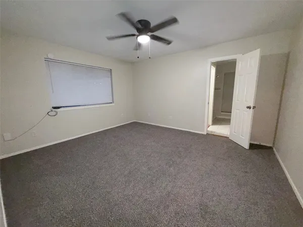 an empty room with a ceiling fan and a window