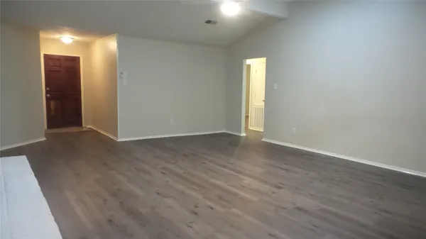 a view of an empty room with wooden floor and a bathroom