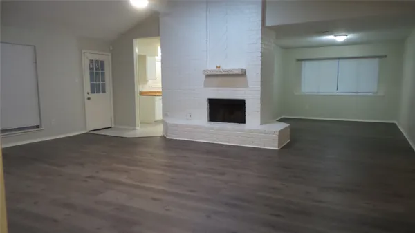 an empty room with wooden floor fireplace and windows