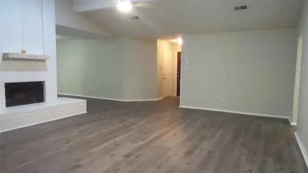 a view of an empty room with wooden floor and a fireplace