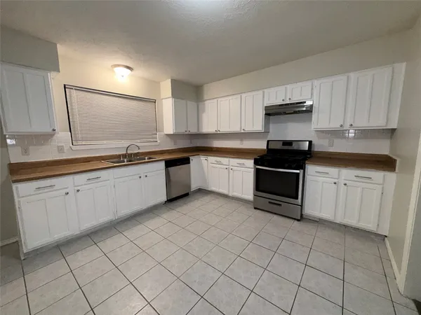 a kitchen with a sink white cabinets and appliances