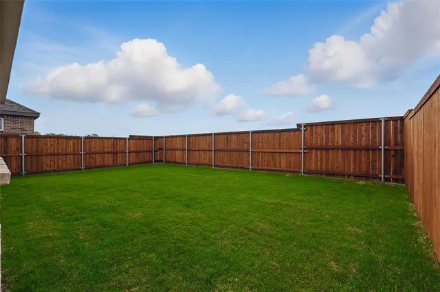 a view of a backyard with grass and wooden fence