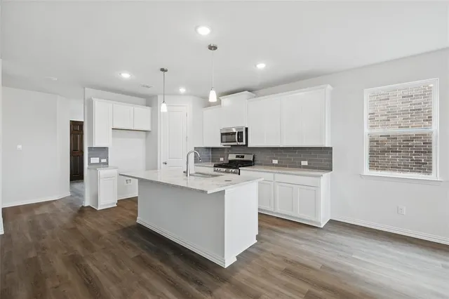 a kitchen with stainless steel appliances kitchen island granite countertop a stove a sink and a refrigerator