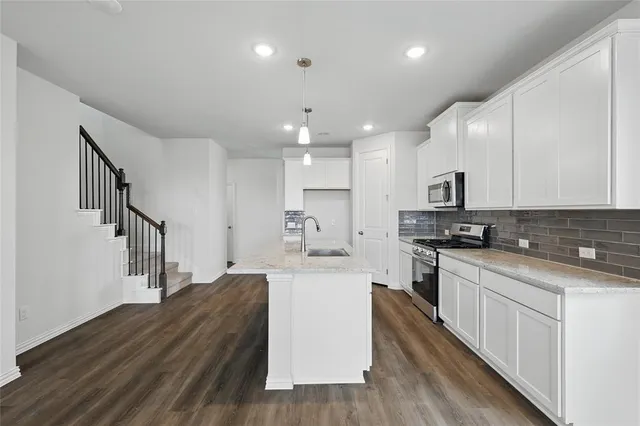 a large kitchen with stainless steel appliances kitchen island a stove a sink wooden cabinets and a refrigerator