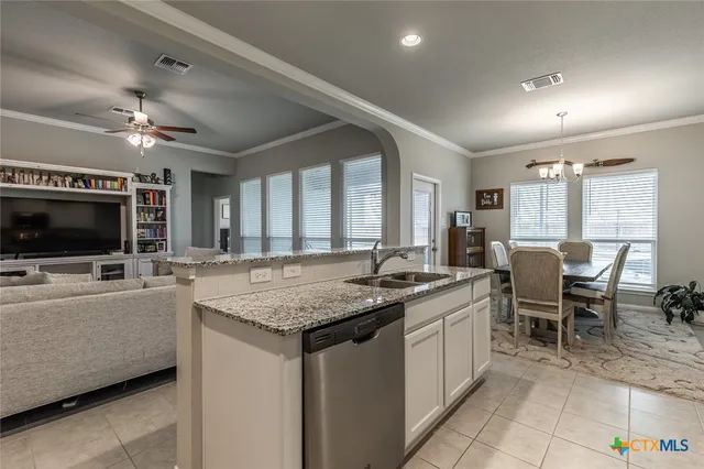 a kitchen with stainless steel appliances granite countertop a refrigerator a stove a sink and white cabinets