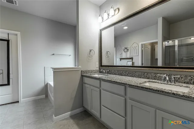 a en suite bathroom with a granite countertop sink and a mirror