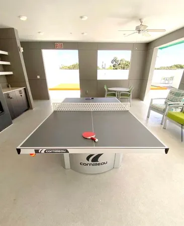 a living room with furniture pool table kitchen view and a flat screen tv