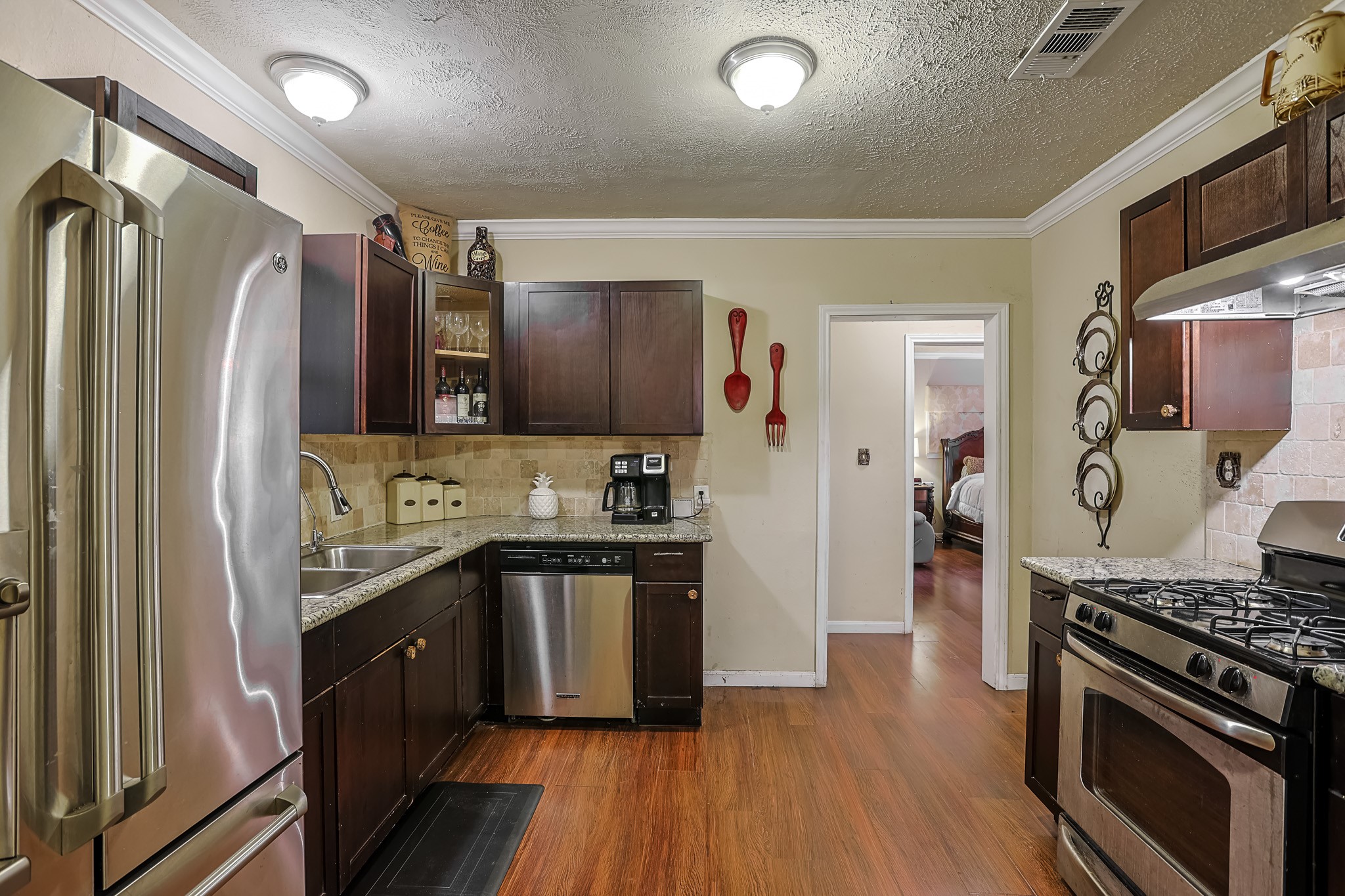 776 Fair Street Houston, TX 77088 - Photo 6 of 14 a kitchen with stainless steel appliances granite countertop a stove top oven a refrigerator and a sink with wooden floor
