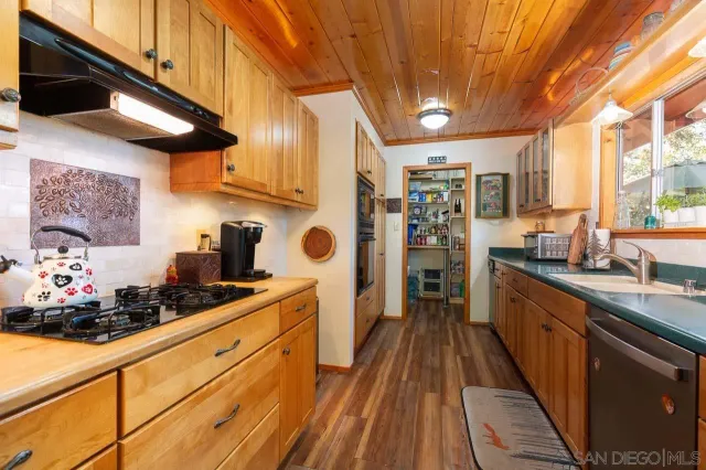 a kitchen with stainless steel appliances granite countertop a sink a stove and a wooden floors