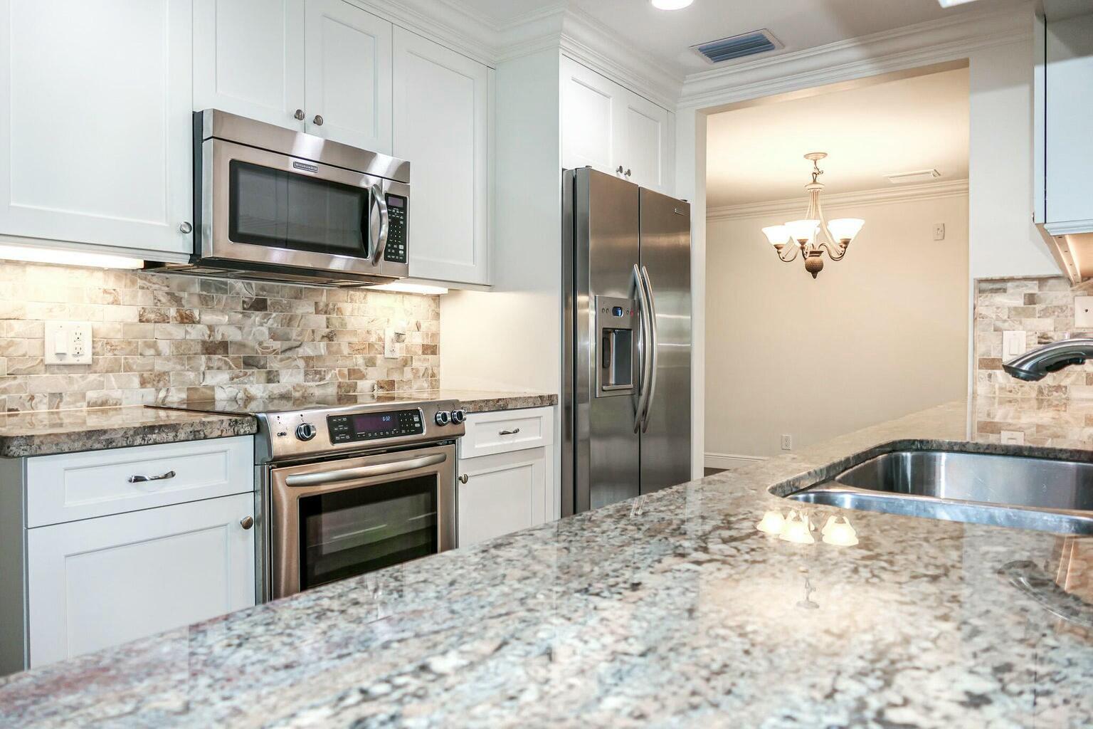 18014 Perigon Way Jupiter, FL 33458 - Photo 12 of 35 a kitchen with granite countertop a refrigerator stove and sink