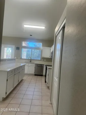 a large white kitchen with a sink a refrigerator and cabinets