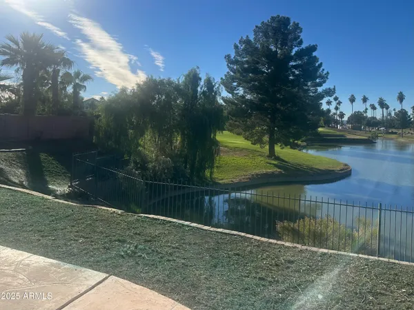 a backyard of a house with lots of green space and lake view in back