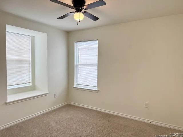 an empty room with windows and fan