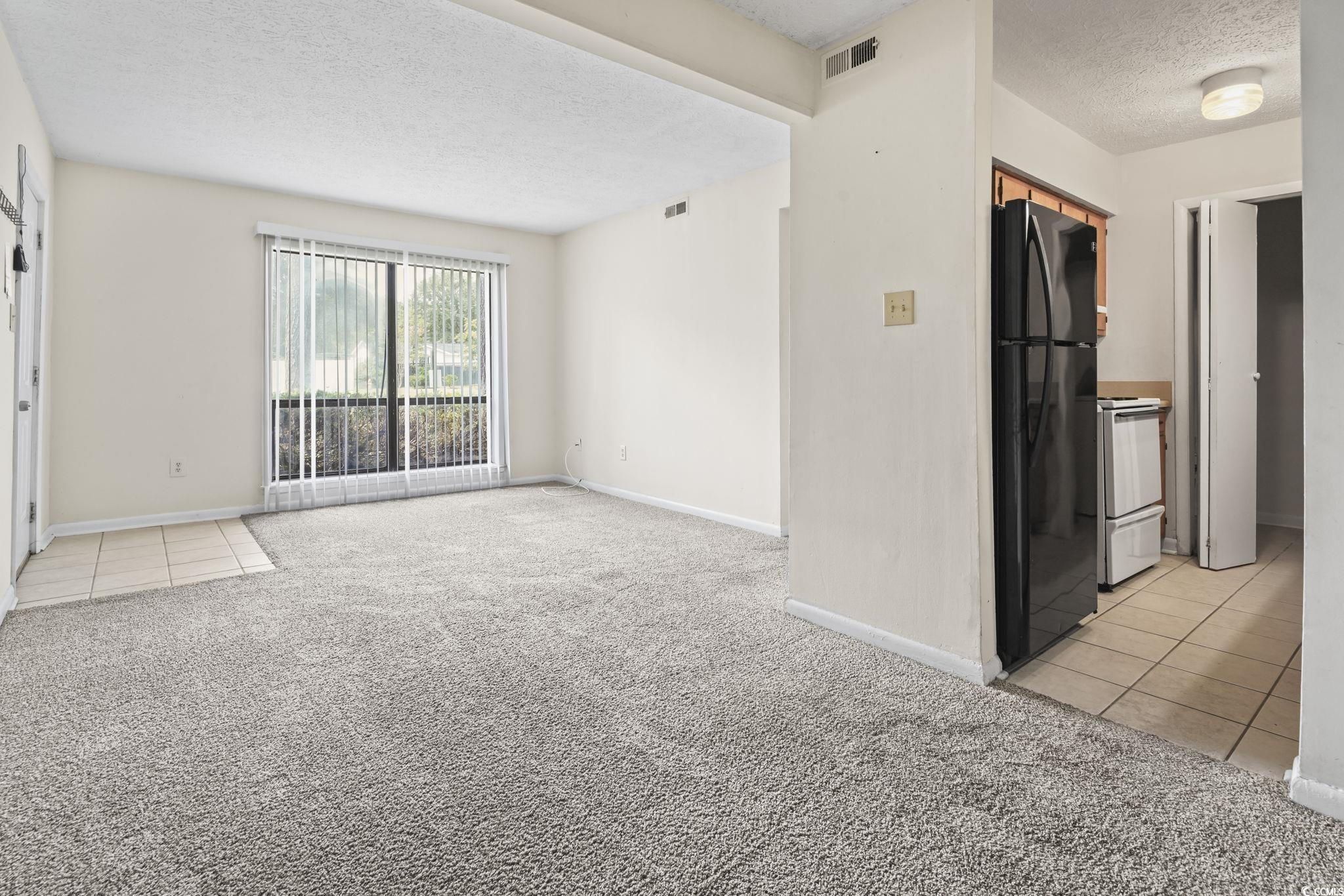615 Carter Lane, Unit A1 Conway, SC 29526 - Photo 15 of 31 Unfurnished living room featuring light tile patterned floors, a textured ceiling, and light colored carpet