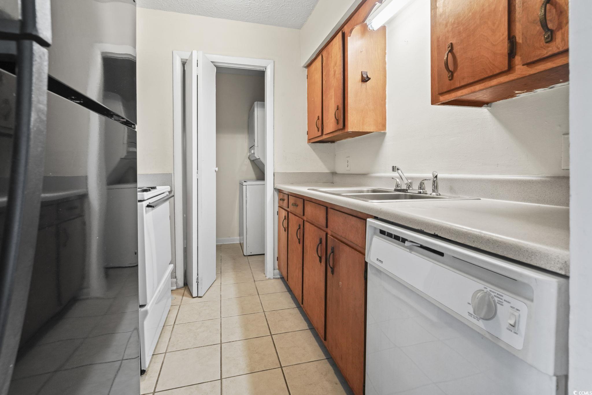 615 Carter Lane, Unit A1 Conway, SC 29526 - Photo 16 of 31 Kitchen featuring brown cabinetry, white appliances, light countertops, light tile patterned floors, and washer / dryer