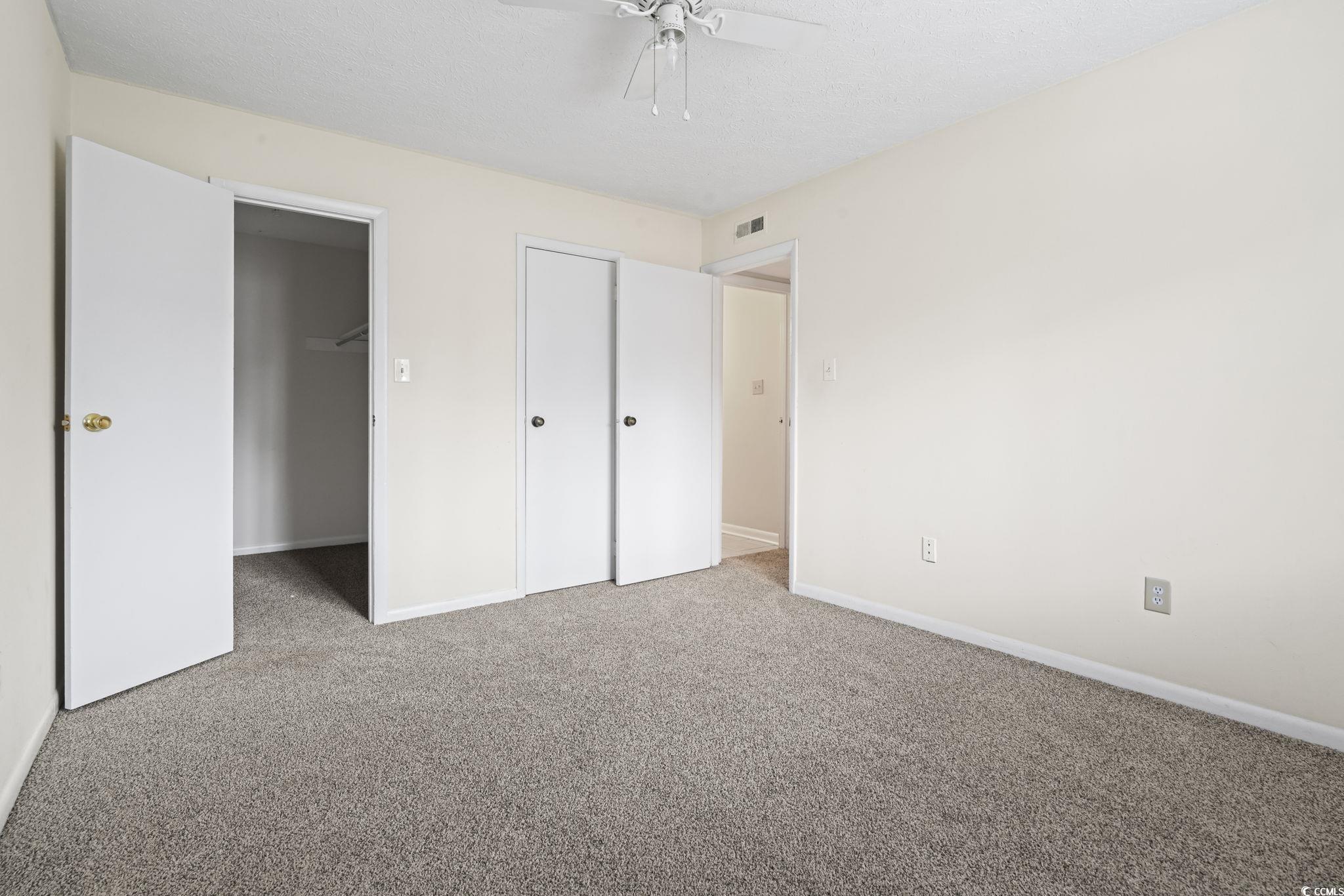 615 Carter Lane, Unit A1 Conway, SC 29526 - Photo 25 of 31 Unfurnished bedroom with carpet, a ceiling fan, a walk in closet, and a textured ceiling
