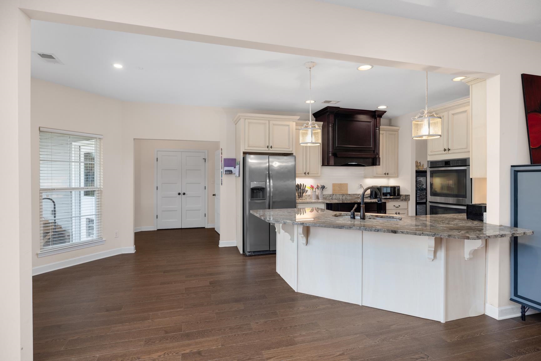 504 Bankston Road Nesbit, MS 38651 - Photo 12 of 39 Open-concept kitchen and living area featuring dark wood-finish flooring, a kitchen island with stone countertops, stainless steel appliances, white cabinetry, and recessed lighting