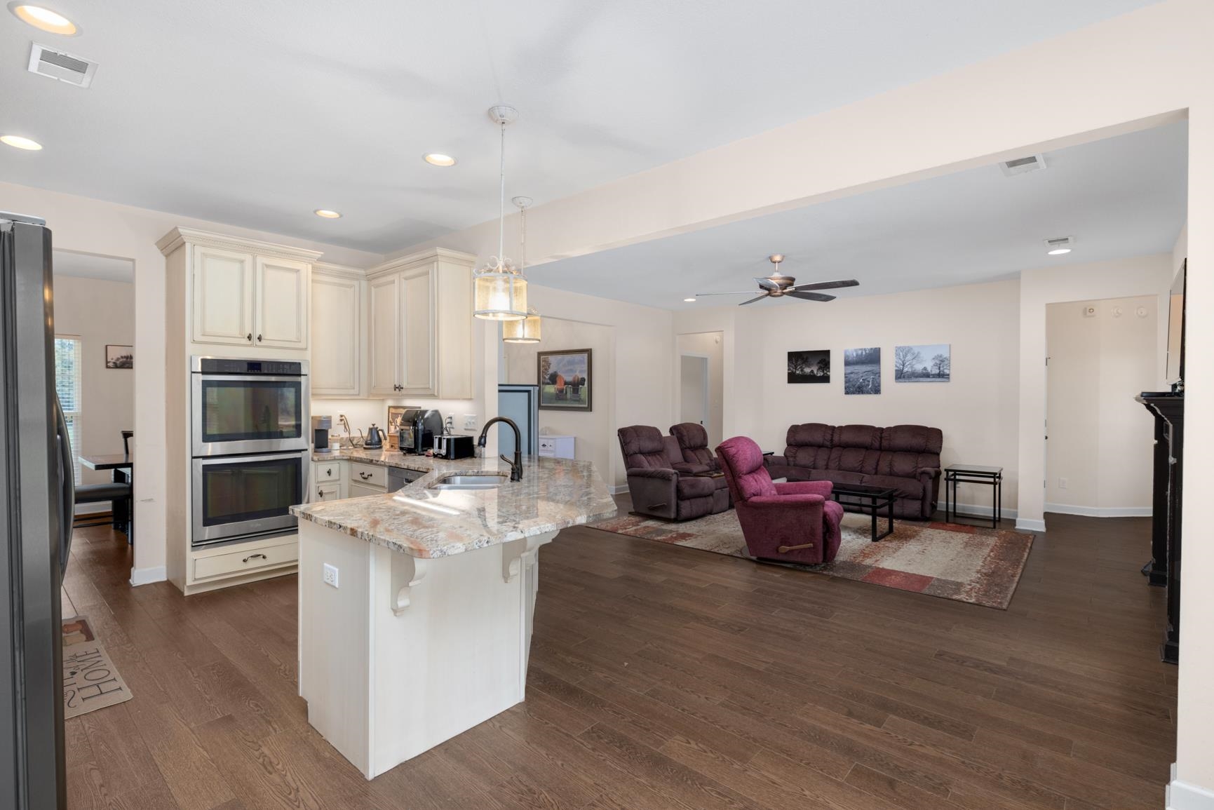 504 Bankston Road Nesbit, MS 38651 - Photo 14 of 39 Open concept kitchen featuring an island with a stone countertop, pendant lighting, stainless steel double ovens, and wood-finish flooring