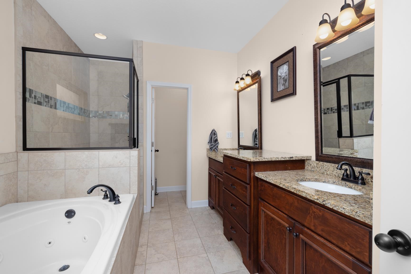 504 Bankston Road Nesbit, MS 38651 - Photo 18 of 39 Spacious bathroom featuring a jetted soaking tub, a separate shower with glass enclosure and tiled accents, dual vanity sinks with granite countertops, and dark wood cabinetry